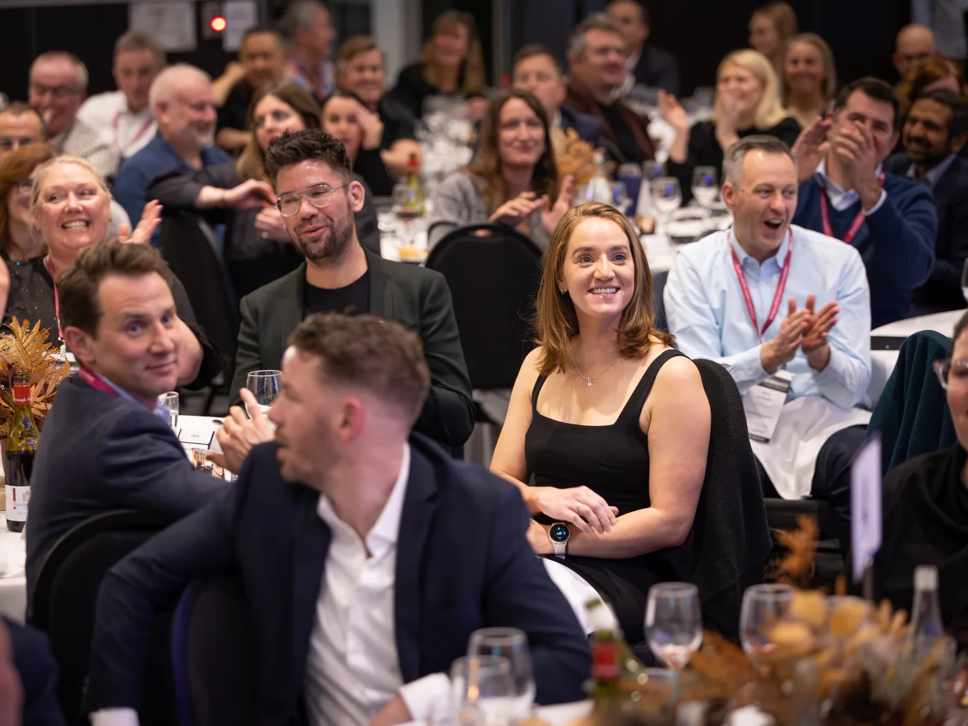 Audience members smiling and applauding during Andy Nunn's keynote